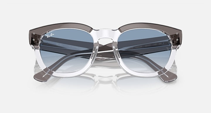 Transparent dark grey sunglasses with blue gradient lenses, angled front view