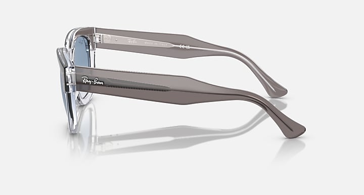 Transparent dark grey sunglasses with metal hinges and light blue lenses, side view