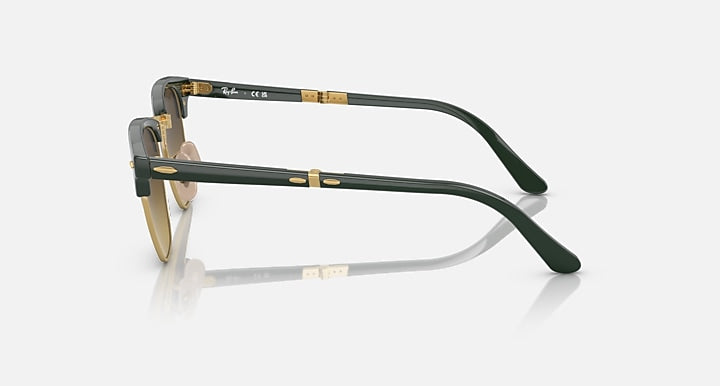 Folding sunglasses side view with dark green temples, gold hinges, brown-tinted lens