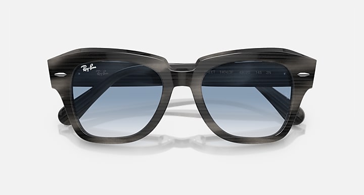 Black sunglasses, angled front view with blue lenses and glossy dark frame