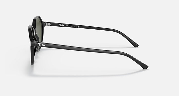 Black round sunglasses side view with dark green lenses and curved temples.