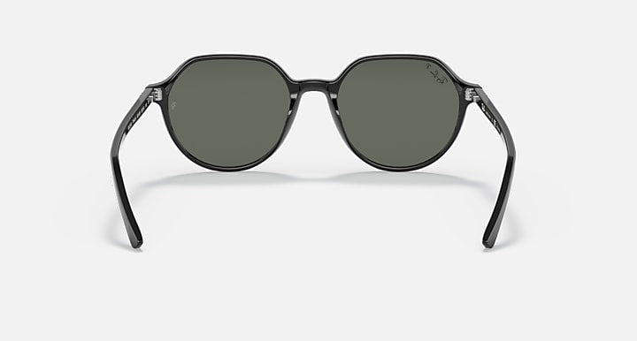 Round black sunglasses with dark green lenses and visible hinge on temples.