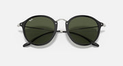 Round sunglasses with dark green lenses, black frame and metal bridge detail.