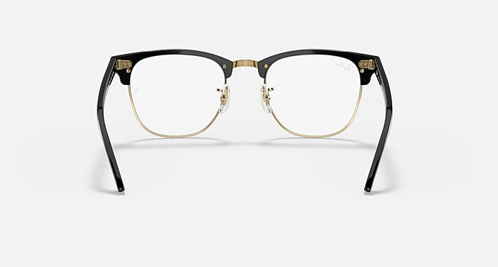 Clubmaster-style sunglasses with black frame, clear lenses, and gold-tone eyeglass rims