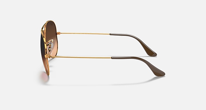 Ray-Ban aviator sunglasses with gold metal frame and dark lenses with brown tips