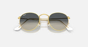 Round metal sunglasses with gold frames and dark lenses, angled side view.