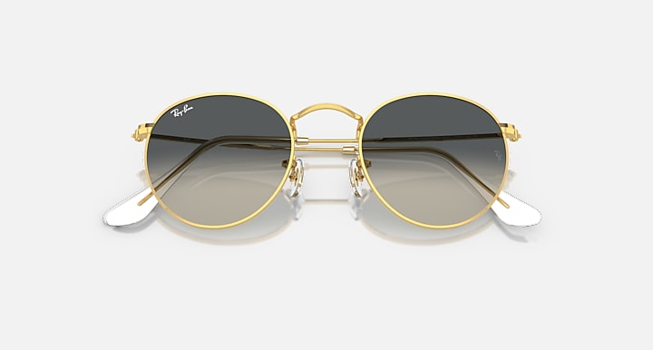 Round metal sunglasses with gold frames and dark lenses, angled side view.