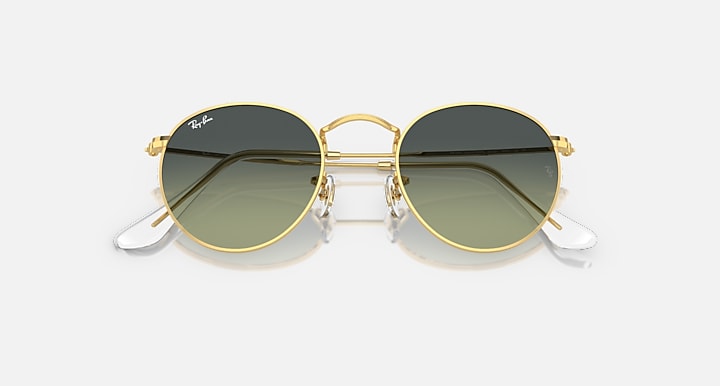 Round metal sunglasses by Ray-Ban, gold frames, dark lenses with white temple tips, angled