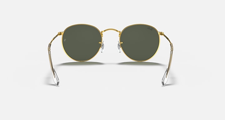 Round metal sunglasses with gold frame and dark green lenses, front view on neutral background.
