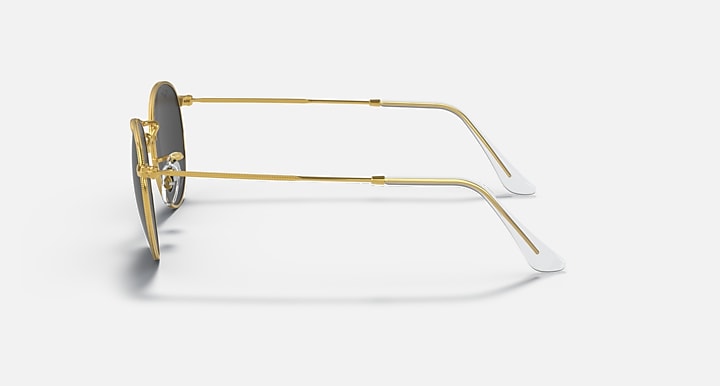 Gold round metal sunglasses in side profile with clear temple tips and lens edge.