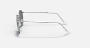 Round metal sunglasses with clear dark gray lenses and shiny silver frame, side view.