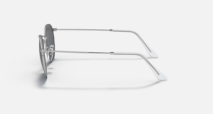 Round metal sunglasses with clear dark gray lenses and shiny silver frame, side view.