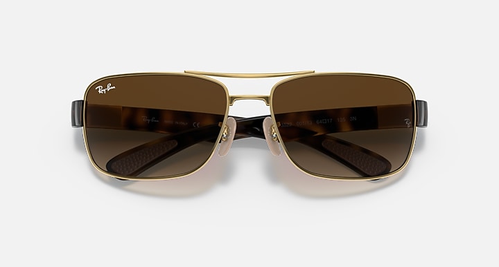 Dark brown gradient sunglasses with gold frame, front view of shield-shaped lenses.