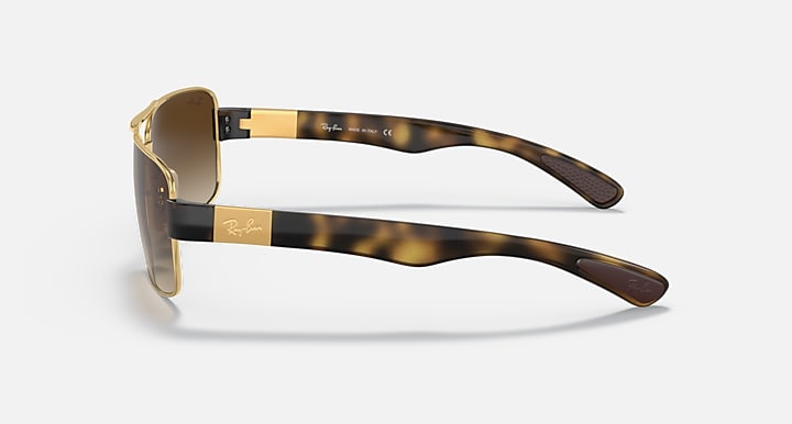 Side view of brown gradient sunglasses with gold frame and tortoise-pattern temples.