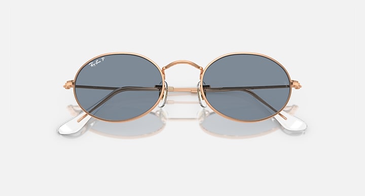 Ray-Ban round sunglasses with blue-gray lenses and rose gold metal frame, angled front view