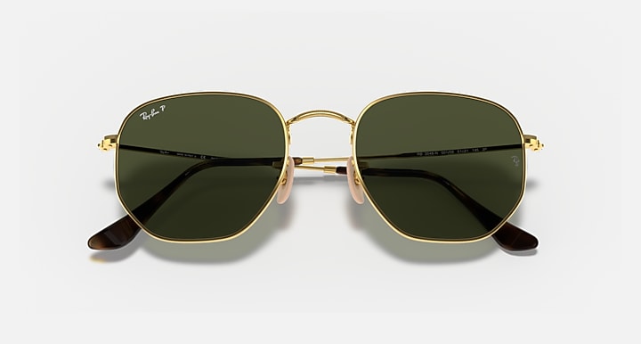 Hexagonal flat sunglasses with gold frame and dark green mirror lenses, angled view