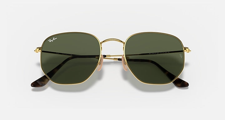 Hexagonal flat sunglasses with gold frame and dark green lenses, black temple accents