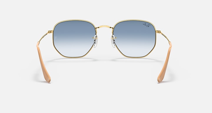 Hexagonal sunglasses, gold frame with blue gradient lenses and orange-brown temple tips.
