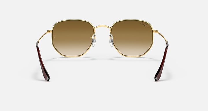 Hexagonal sunglasses front view, gold frame with brown lenses and burgundy temple arms.