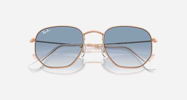 Ray-Ban hexagonal sunglasses angled front with rose-gold frame and blue tint