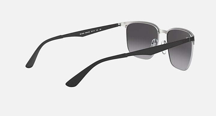 Sunglasses with dark gray lenses and silver frame in angled side view; temple visible