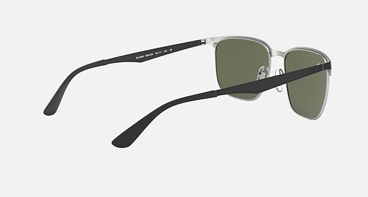 Sunglasses with green lenses and silver frame in angled side view; visible temple logo
