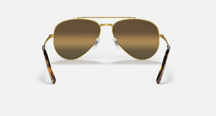 Aviator sunglasses with gold frame and dark brown gradient lenses; tortoiseshell temple tips