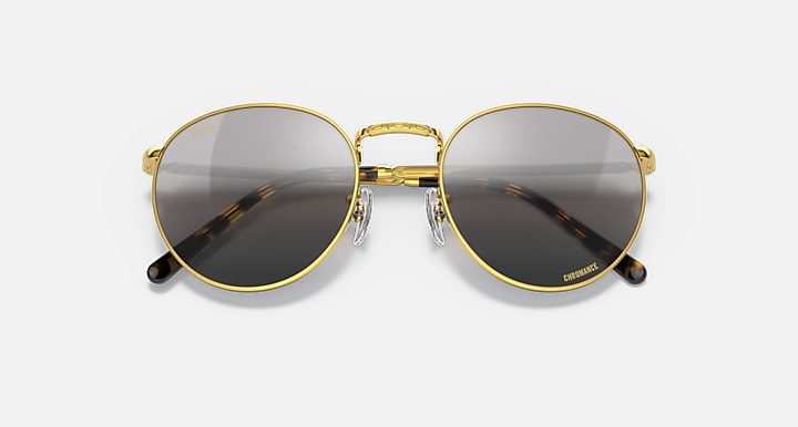 Round gold metal sunglasses with dark lenses, gold bridge, and patterned temple detail