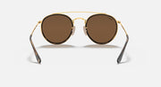 Round sunglasses with gold metal frame and medium brown lenses, double bridge.