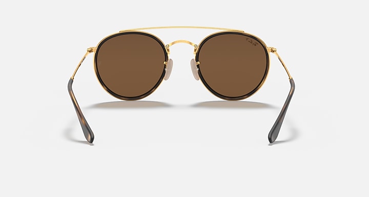 Round sunglasses with gold metal frame and medium brown lenses, double bridge.