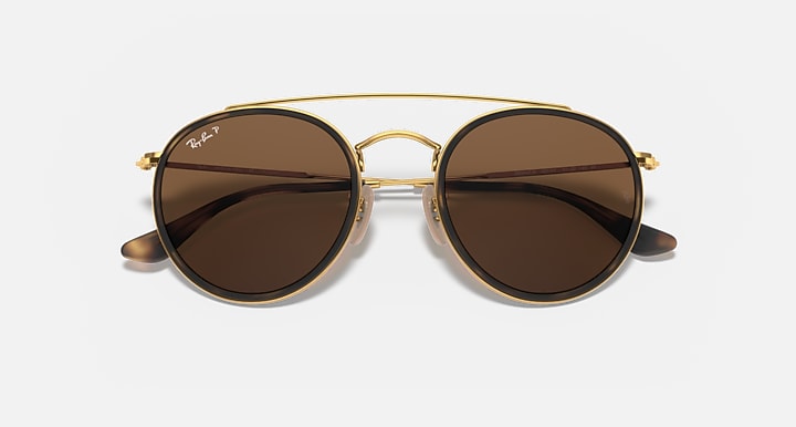 Round sunglasses with gold metal frame and dark brown lenses, double bridge and curved arms.