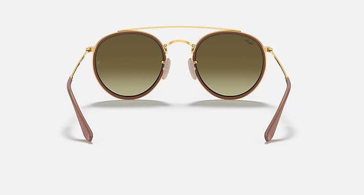 Round sunglasses with gold metal frame and dark green-tinted lenses, double bridge.