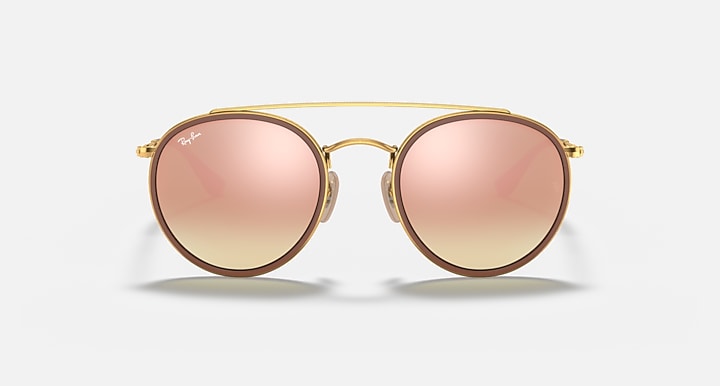 Round sunglasses with gold metal frame and soft pink gradient lenses, double bridge detail.