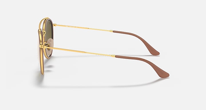 Gold metal round sunglasses showing temple arms with brown tips and double bridge.