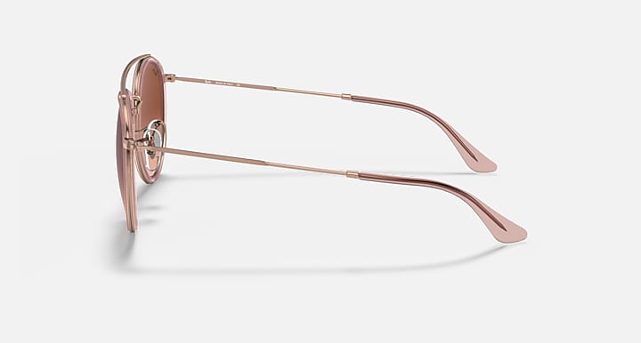 Rose-gold metal sunglasses with round brown lenses, side profile and temple arms