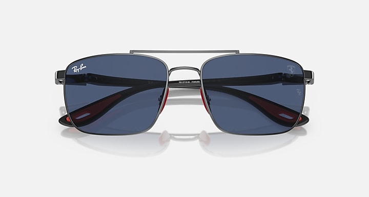 Sunglasses front with dark blue lenses and gunmetal frame, red inner temple accents
