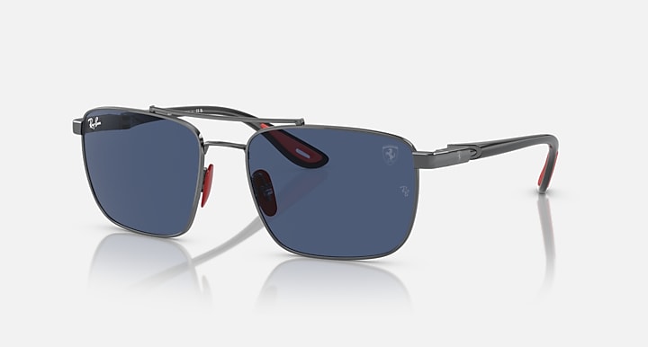 Sunglasses with dark blue mirrored lenses, gunmetal frame, red accents at temples