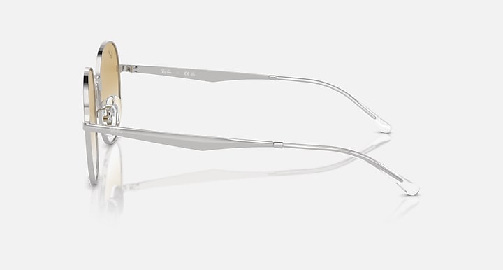 Side view of round sunglasses with silver metal frame and tan gradient lenses