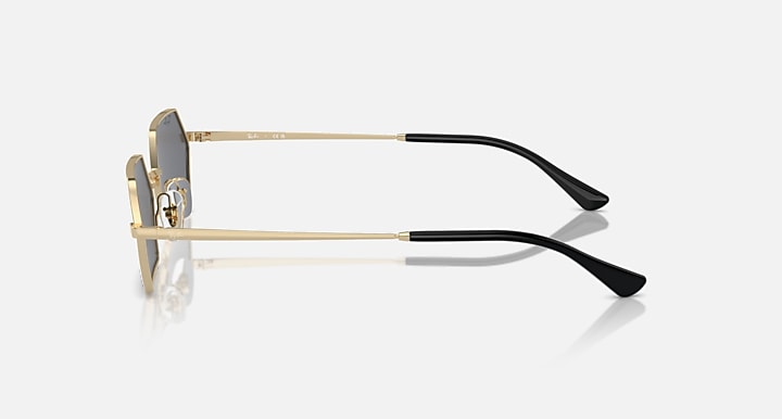 Hexagonal sunglasses side view with dark lens and light gold frame, black tips