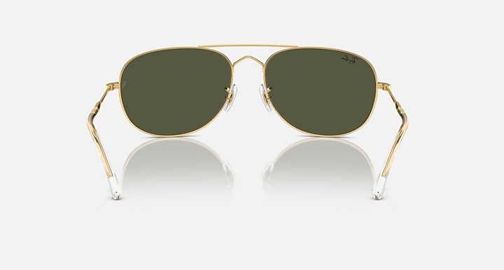 Gold oval sunglasses with dark green lenses, metal bridge, and clear-tipped arms
