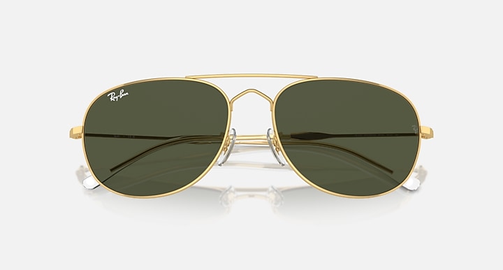 Gold oval sunglasses with dark green lenses and mirrored reflection on glass