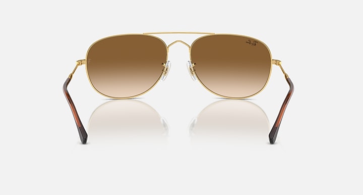 Gold oval sunglasses with brown gradient lenses, metal bridge, and clear arms