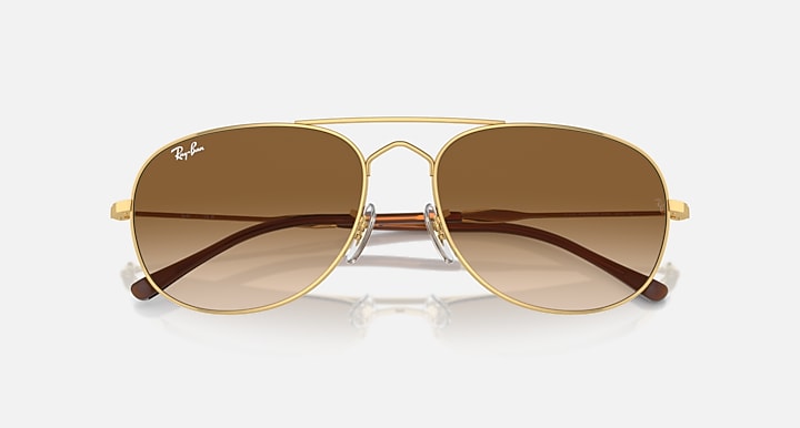 Gold oval sunglasses with brown gradient lenses and front bridge hardware