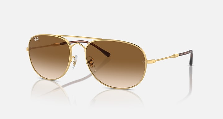 Gold oval sunglasses with brown gradient lenses and clear metal rim detailing
