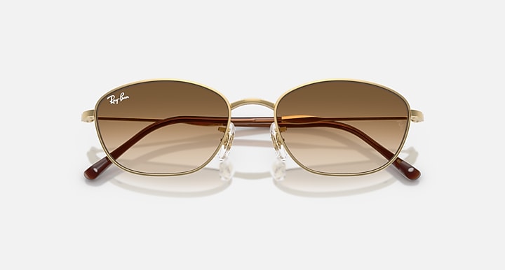 Gold oval sunglasses with medium brown lenses and dark brown temple accents