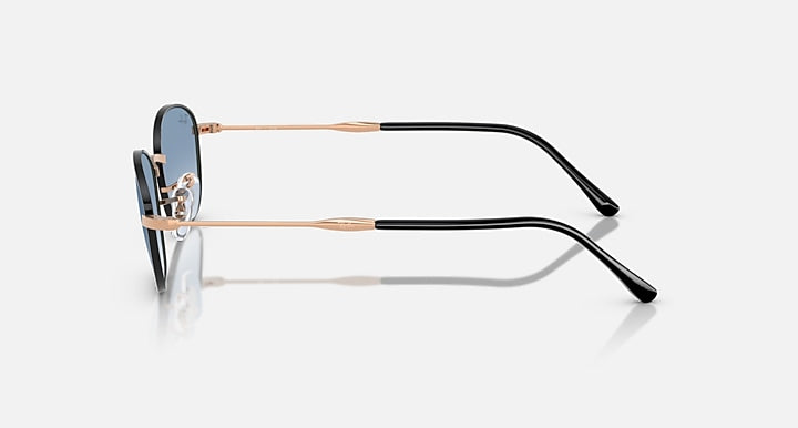 Sunglasses with blue tinted lenses and rose-gold/black metal frames, side view.