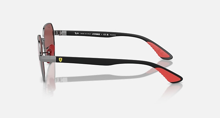Sunglasses side view with dark frame, red accent on temple tips, tinted lenses.