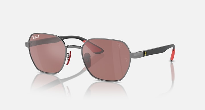 Sunglasses with dark frame and rose-brown gradient lenses, black temples with red tips.