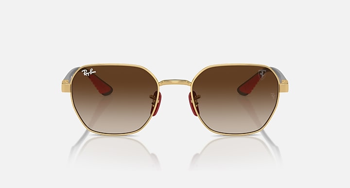 Sunglasses with gold frame and warm brown lenses, small red accent at hinges.