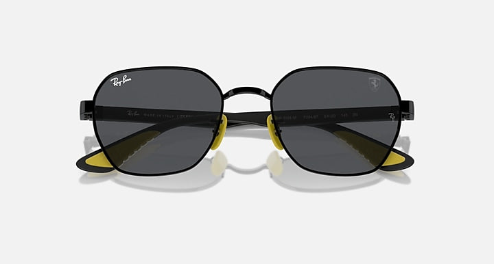 Black oval sunglasses with dark lenses, yellow hinge details and slim metal arms